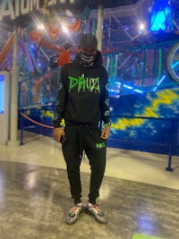 a man in a black hoodie standing in an amusement park